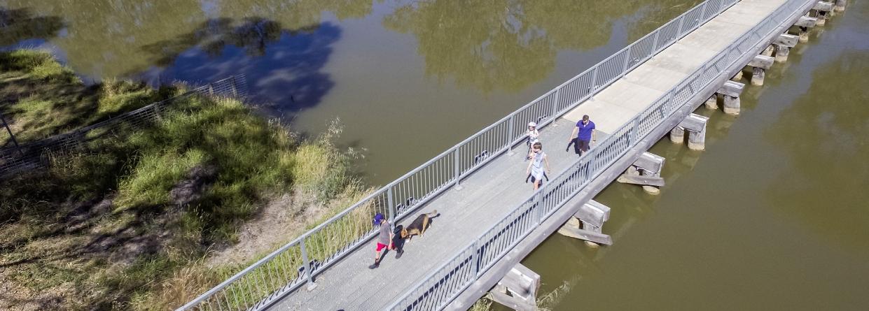 Photo of people walking across a bridge over a body of water.