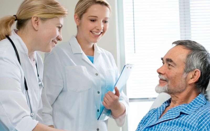 Photo of doctor and medical student greeting a patient.