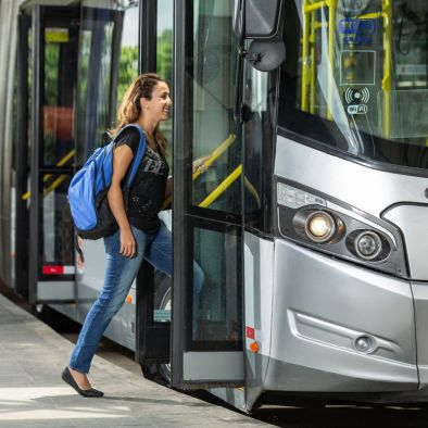 Photo of a lady wearing a backpack entering a bus.